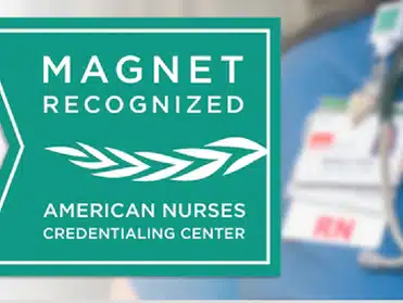 "Magnet Recognized" emblem by the American Nurses Credentialing Center with a blurred background of nursing credentials.