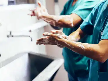 Healthcare professionals washing their hands thoroughly in a sink.