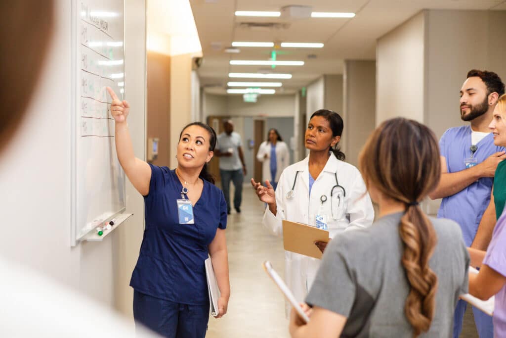 Healthcare staff discussing patient care planning in a hospital hallway, representing AI-powered staff forecasting.